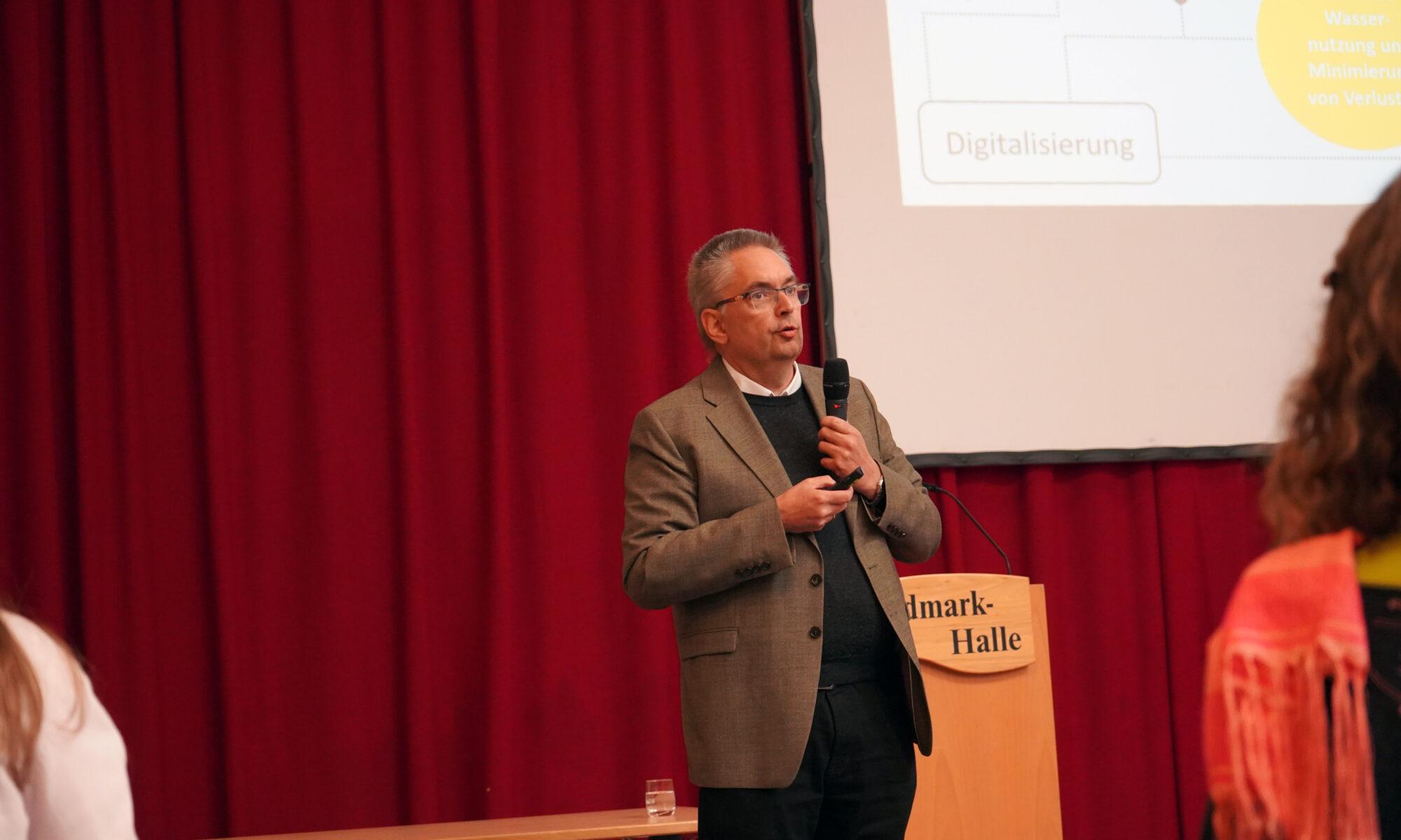 Prof. Dr. Klaus Röttcher bei seinem Vortrag mit dem Titel "Natürlichen Wasserhaushalt verstehen und Ableitung von Handlungsoptionen für Kommunen" in der Heidmark-Halle in Bad Fallingbostel. Foto: Marie Ruhm/Ostfalia